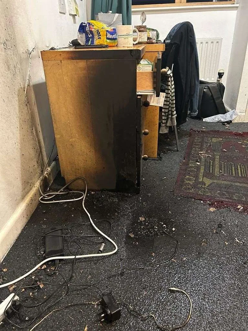 Pomieszczenie z meblami uszkodzonymi przez pozar i zagracona podloga.