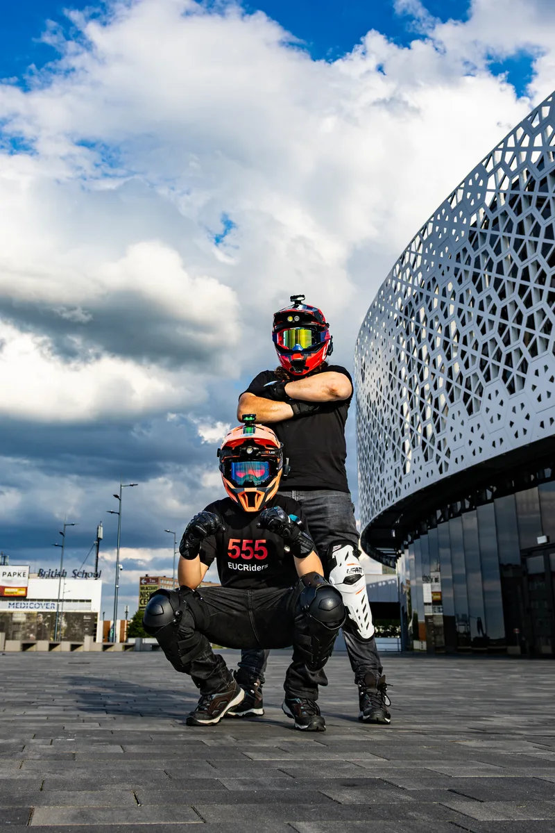 Two 555 EUCRiders posing in helmets outside Urania in Olsztyn.